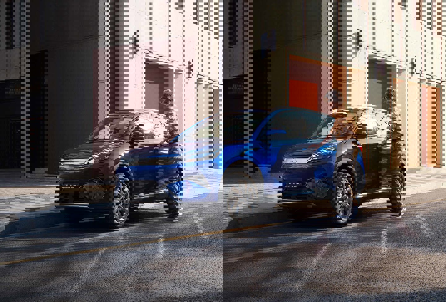 En blå bil parkeret på en gade foran en bygning, hvor den livlige farve skiller sig behageligt ud mod byens baggrund.