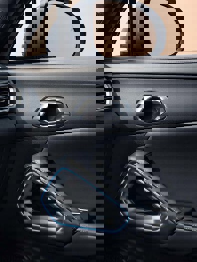 En persons hånd holder fast i rattet inde i en bil, med et kreativt og farverigt digitalt kunstnerisk præg over billedet.