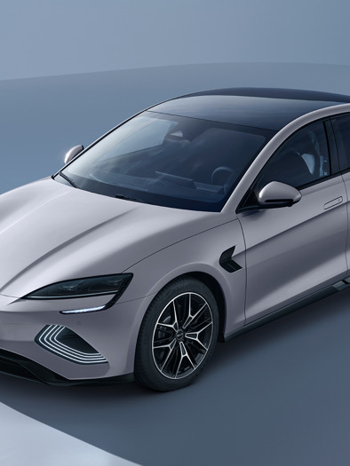 En slank, sølvfarvet elektrisk BYD SEAL sedan med sort tag og moderne design, parkeret i et minimalt, lysfyldt studie.