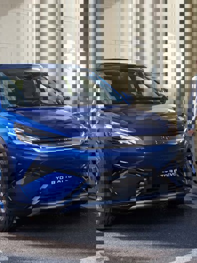 En blå bil kører på en gade i byen.