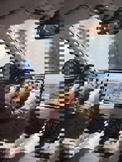 To personer sidder i en bil; den ene kører, mens passageren bruger en smartphone monteret på instrumentbrættet til navigation.