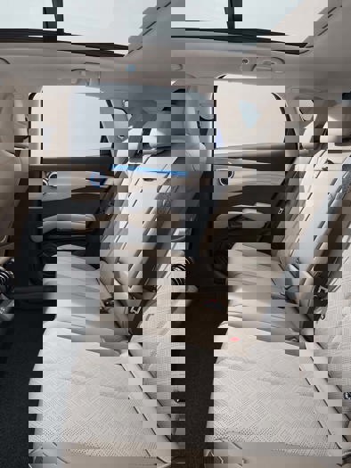 Et bilinteriør med lyse lædersæder og rent betræk.