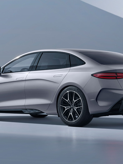 En slank, sølvfarvet BYD Seal elektrisk sedan er parkeret i et minimalistisk, lysegråt studie, vist fra bagsiden.