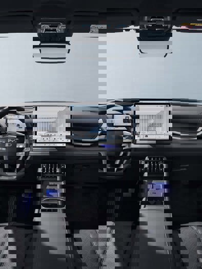 Moderne bilinteriør med synligt instrumentbræt, rat og forsæder.