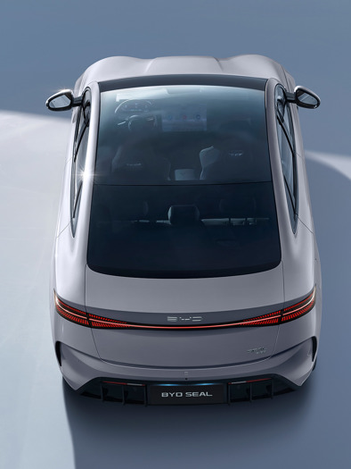 En sølvfarvet BYD Seal-elbil set ovenfra, der viser sit panoramaglastag og slanke, moderne design på en glat overflade.
